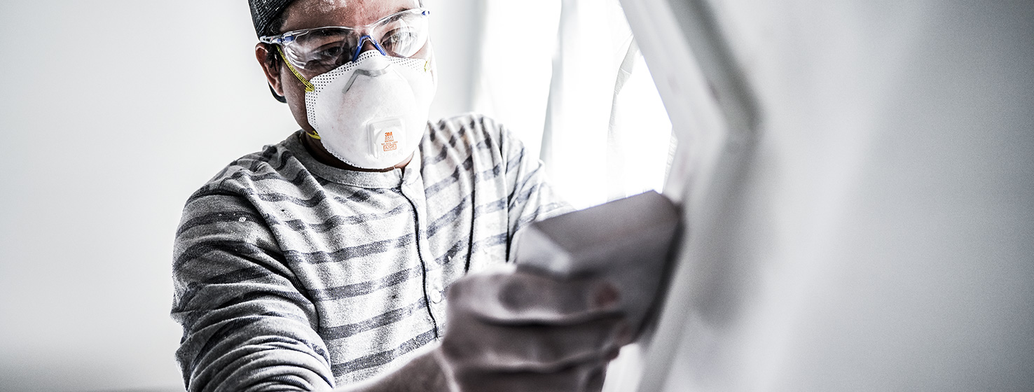 Man sanding a wall